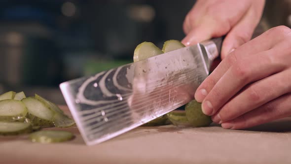 The chef professionally slices a cucumber