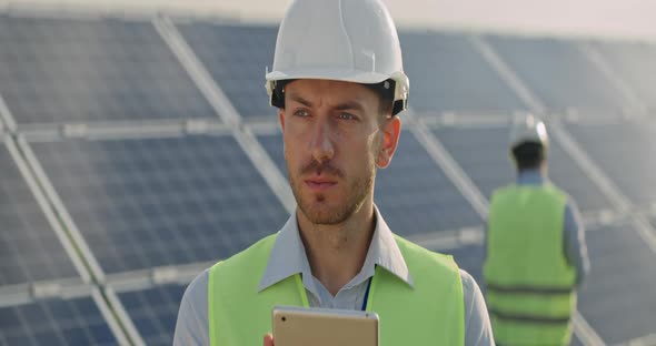 Close Up View of Male Engineer Looking at Tablet Screen and Than Aside. Man in Hard Helmet and alt
