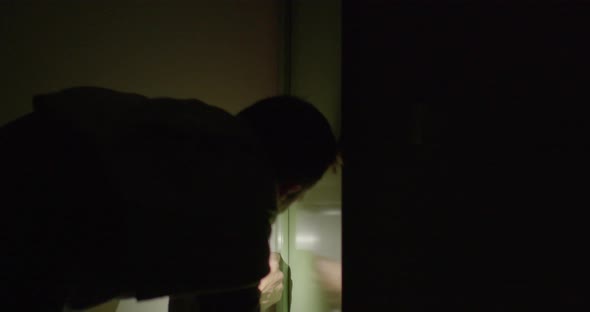 A Man with a Flashlight in His Hands in a Dark Room Opens the Lock with a Key alt