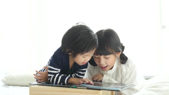 Cute Asian Children Reading A Book On White Bed alt