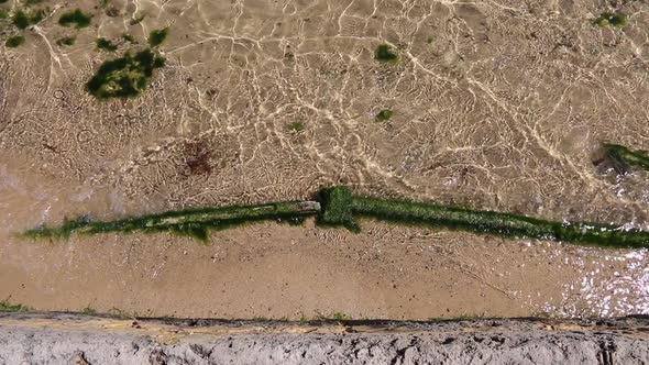 Gentle waves and clear water lapping over the old Swan River sea wall alt