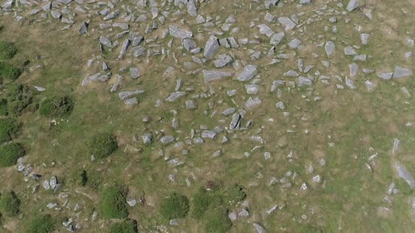 Birdseye aerial tracking backwards over rocks in a moorland setting ...