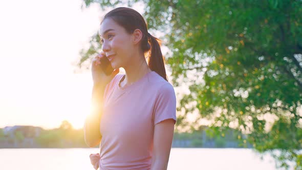 Asian young woman stand outdoor use mobile phone call talk with friend. alt