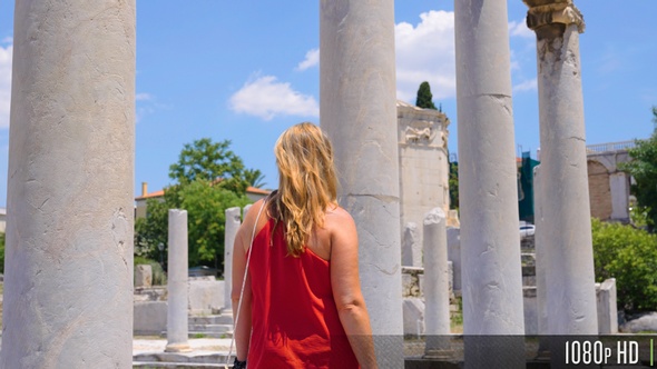 Woman Walking in Slow Motion Next to Ancient Greek Columns in the Roman Forum of Athens, Greece alt