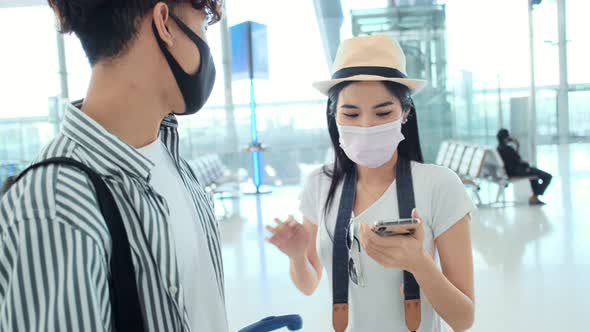 Asian male and female wearing protective face mask in airport terminal alt