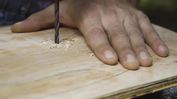 Crafstman drilling hole in wooden plank for skateboard wheels to attach, close motion view alt