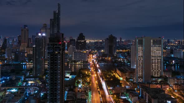 Bangkok traffic toward downtown on Taksin bridge over Chao Phraya river at night - time lapse