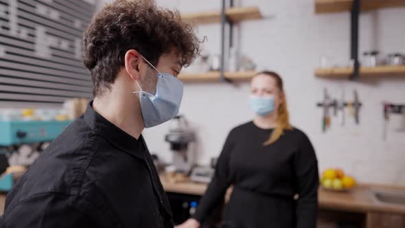 Side View Portrait of Young Middle Eastern Man in Covid19 Face Mask Ordering in Cafeteria on alt