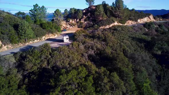 Fly over White RV parked in California Mountains at Dawn, Drone Reveal alt