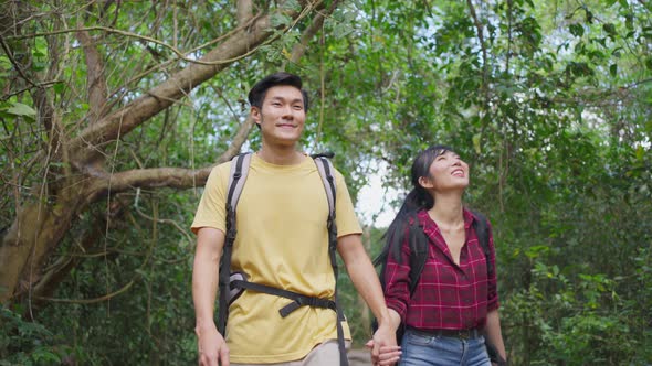 Young Asian man and woman friend traveling in the forest together, walking with happiness and fun. alt