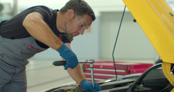 Car Mechanic Repairing a Car with Socket Wrench. Car Mechanic Using a Screw Wrench To Tighten the alt