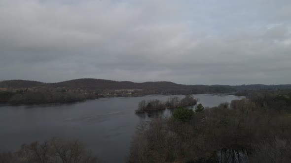 View over lake on a dark and stormy day. Mountains seen in the distance with forest,