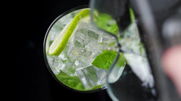 Close-up Refreshing Soda Tonic. Pour Carbonated Water Into a Glass of Lime and Ice. Cold Mojito alt