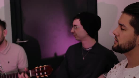 Three Men Sit Sing Play Guitar alt