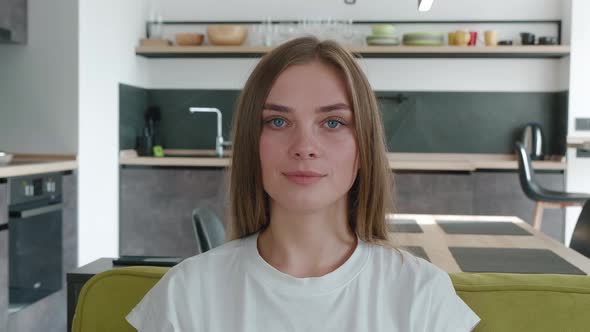 Close Up Portrait of Attractive Young Woman Sitting on the Sofa in Cozy Living Room, Looking at the alt