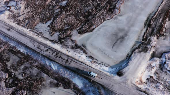 Aerial Top Down View Tracking Van Car Driving Moving in Winter on Road Through Wild Snowy Rocky Land alt