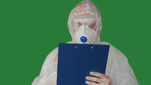 Medical Worker in Protective Costume and Mask Writing on Clip Board alt
