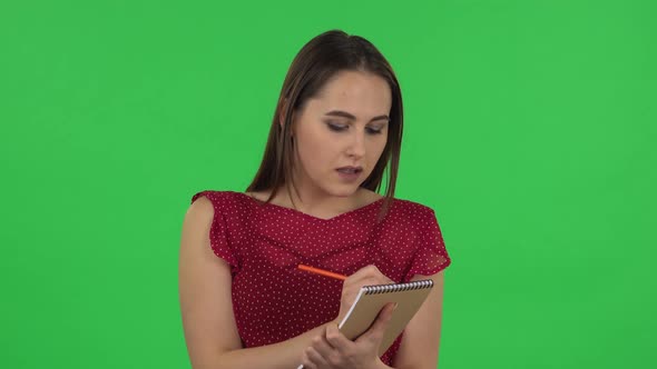 Portrait of Tender Girl in Red Dress Is Standing and Thinking, Then Happy Writing with Pencil in alt