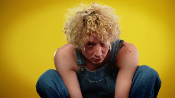 Portrait of Caucasian Androgynous LGBT Man Sitting on Hunkers Looking at Camera alt