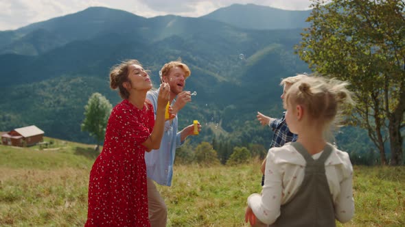 Parents Blowing Soap Bubbles on Green Meadow alt