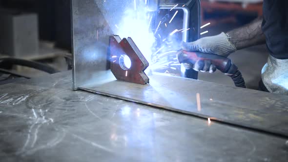 Welder at Work. Worker Welds Metal Parts. Welding Process, Sparks, Flame, Smoke.