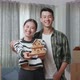 Young Asian Couple With Cardboard Boxes On The Floor Smiling And Showing House Model To Camera - VideoHive Item for Sale