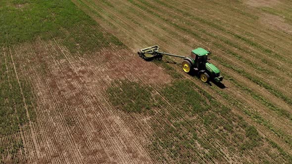 Aerial View of a Tractor with a Mower Mows the Grass on an Empty Field alt