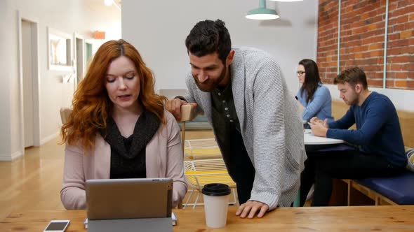 Business executives discussing over digital tablet alt