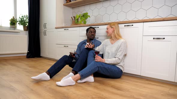Smiling Multiethnic Family Couple in Love Talking Drinking Wine Sitting on Floor alt
