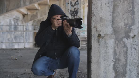 A Man Secretly Takes Photos with a Longfocus Lens While Hiding in an Abandoned Building
