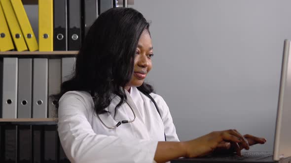 Young African Woman Doctor Works with a Laptop alt