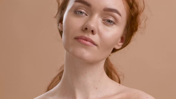 Attractive RedHaired Young Woman Posing Shirtless Over Beige Background alt
