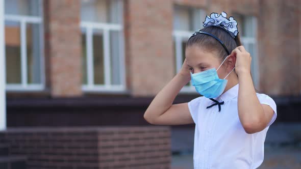 Outdoors Portrait of Schoolgirl, Teenage Girl, Wearing a Medical Protective Mask, on the Background alt