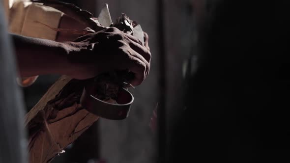 Local Indian man shaping traditional leaf plates with shears alt