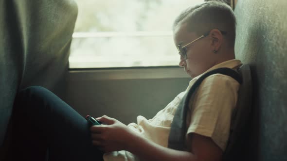 School Boy Using Gadget Playing Games in School Bus alt