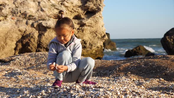 Happy Little Girl Enjoying Summer Vacation and Playing Seashells on the Beach.
