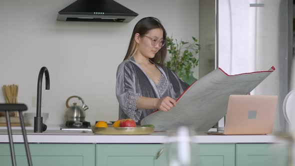 Young Professional Female Asian Architect Looking at Laptop Screen Shaking Head Yes Examining alt