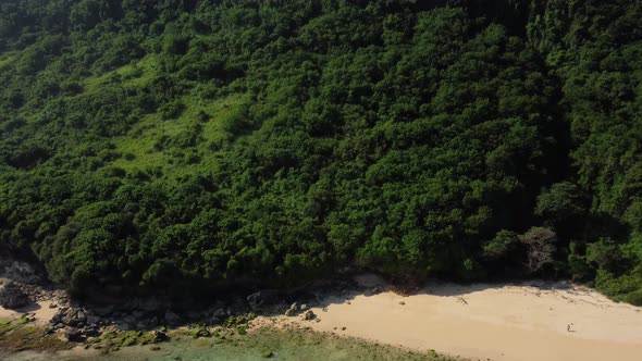 Aerial zoom in on green cliff in Nunggalan beach alt