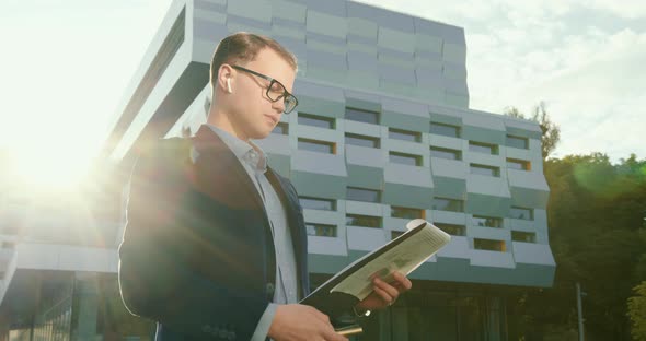 The Businessman Is Looking Through Documents and Making Notes with a Pen alt
