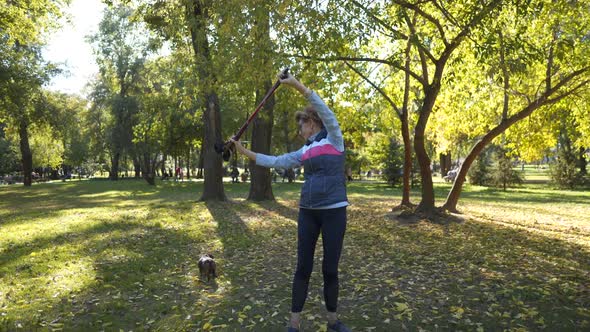 Mature Woman Doing Exercises with Nordic Walking Poles in the Park in Sunny Autumn Weather alt