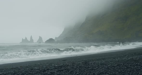 The Black Sand Beach of Reynisfjara with Waves Hitting the Shore on Foggy Rainy Stormy Day alt