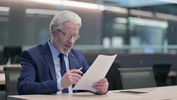 Old Businessman Reacting to Loss on Documents in Office alt