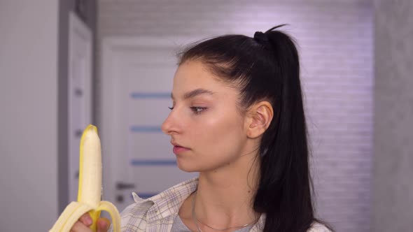 Young Woman Peeling Banana Biting