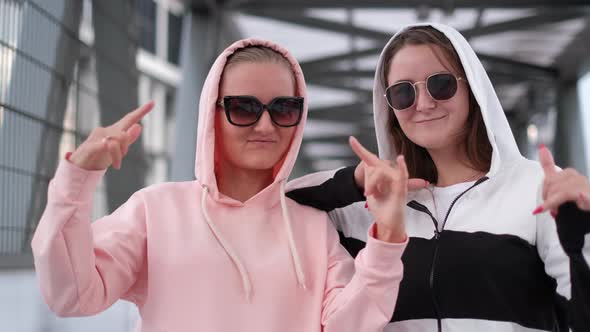 Two fashionably dressed girls dance in the middle of the street. Cool dance of two girlfriends. alt