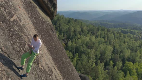 A Young Man Descends From a Rock Mountain on a Rope. alt