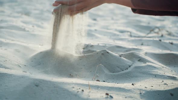 SLOW MOTION, CLOSE UP: The Sand Passes Through the Fingers of a Young Woman. The Sand Is Running alt