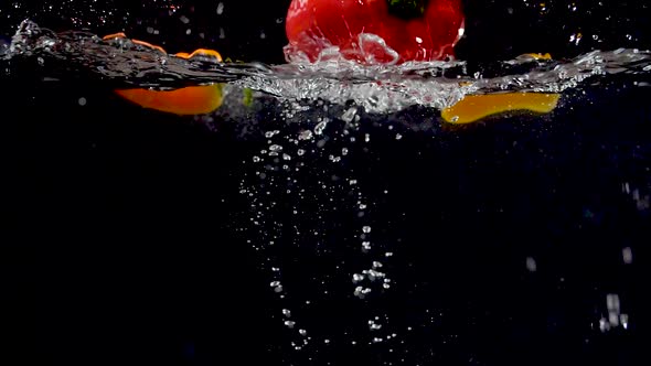 Vibrant bell pepper being dropped into water in slow motion. alt