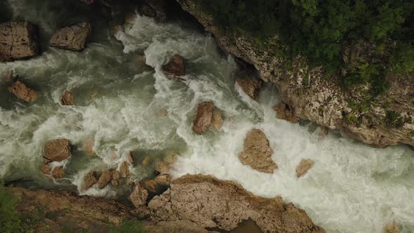 Aerial Drone Top View of a Deep Hadzhokh Gorge and Fast White Stream of River Belaya  alt