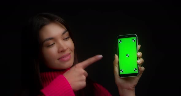 Woman in a Pink Sweater Shows Vertical Green Phone Screen for Copying