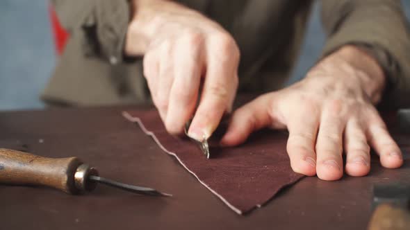 Guy Working with Leather Using Crafting Tool at Workshop